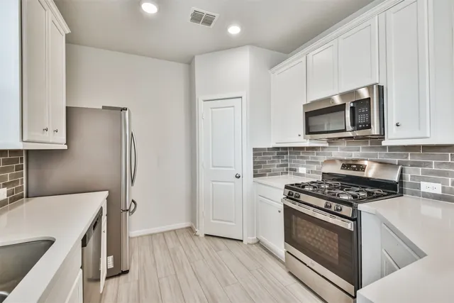 a large kitchen with kitchen island a stove a sink dishwasher and a fireplace with wooden floor