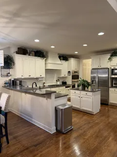 a kitchen with stainless steel appliances a sink a stove a refrigerator cabinets and a wooden floor