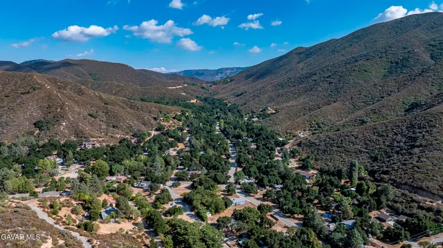 a backyard of a house with table and chairs under an umbrella