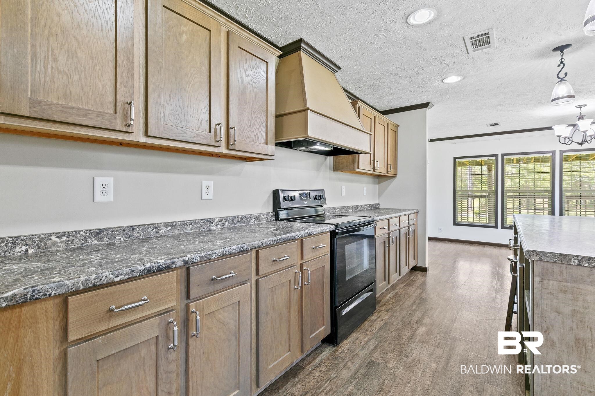35641 County Road 39 Stapleton, AL 36578 - Photo 15 of 46 Kitchen with black / electric stove, decorative light fixtures, premium range hood, dark hardwood / wood-style floors, and a chandelier