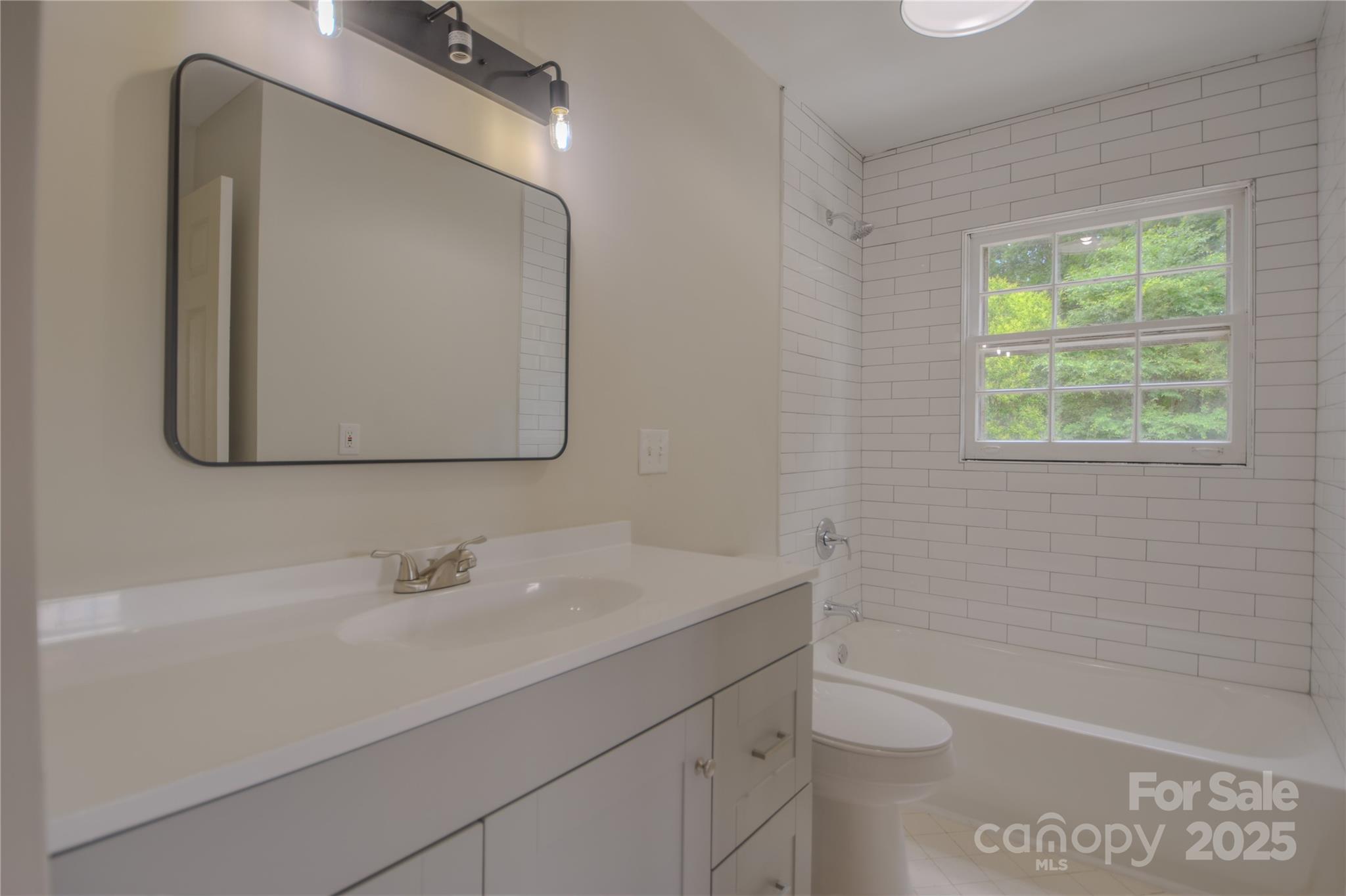 6921 Idlewild Road Charlotte, NC 28212 - Photo 12 of 29 a bathroom with a sink a toilet a mirror and shower