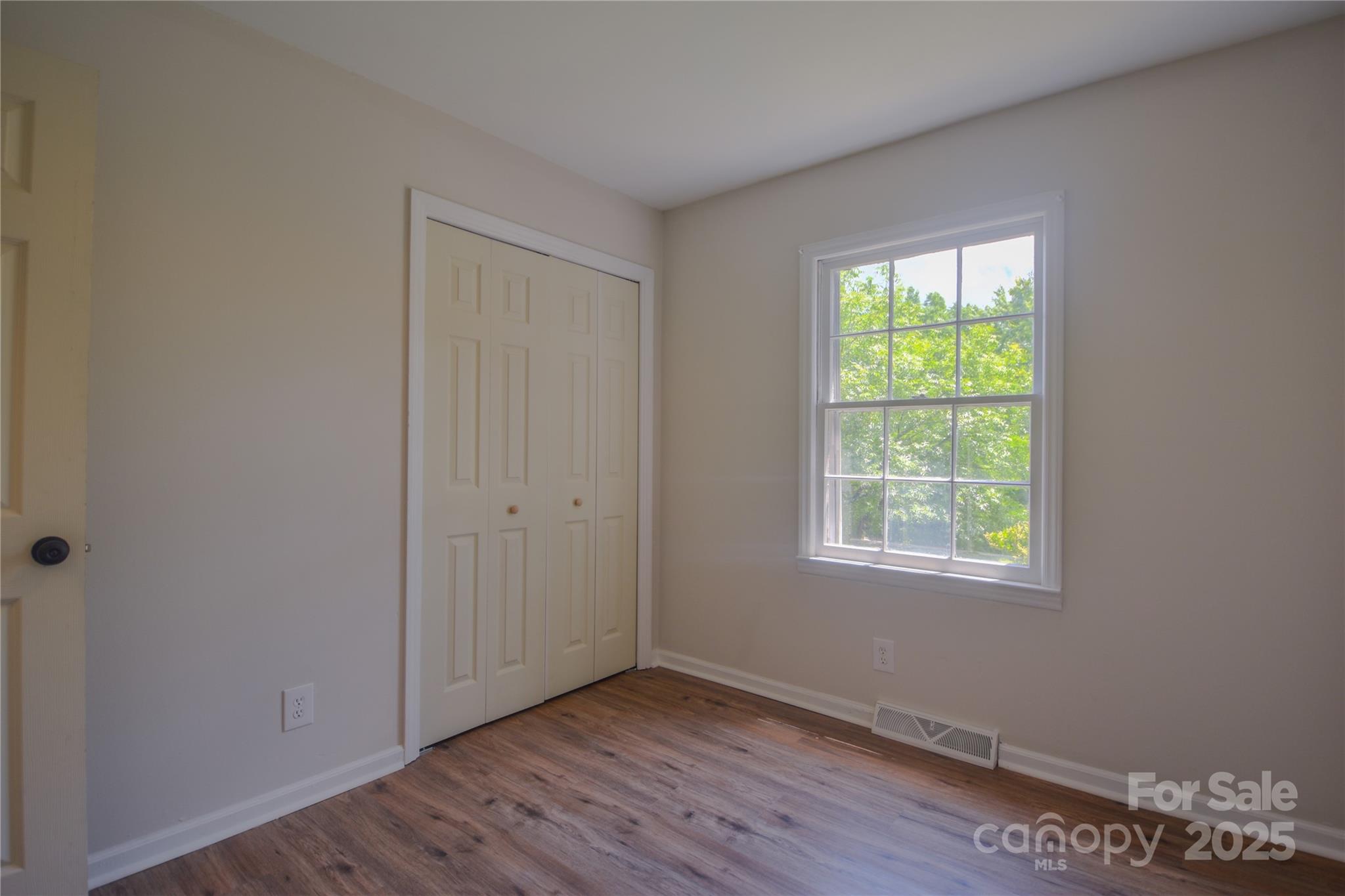 6921 Idlewild Road Charlotte, NC 28212 - Photo 13 of 29 an empty room with wooden floor and windows
