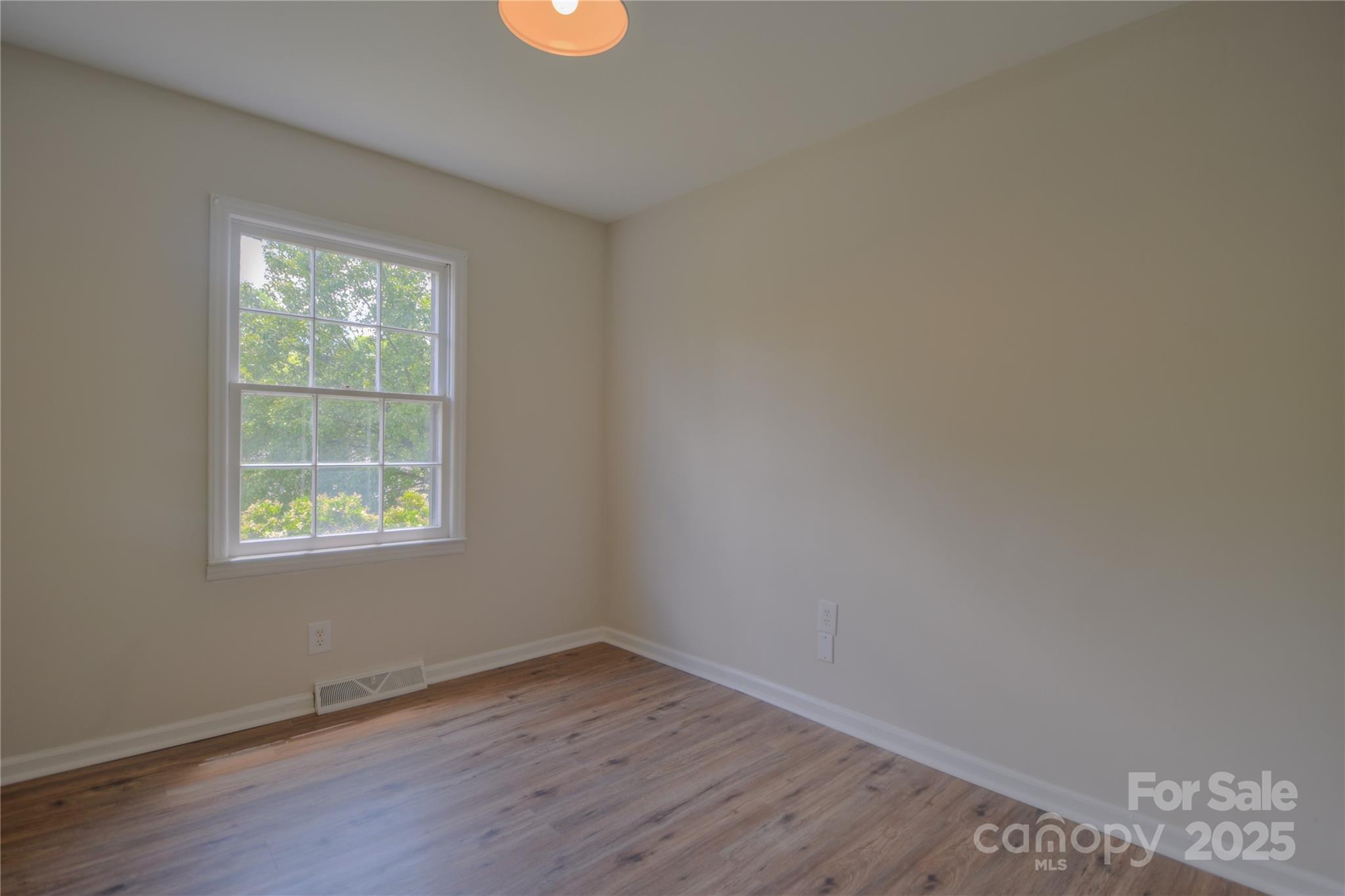 6921 Idlewild Road Charlotte, NC 28212 - Photo 14 of 29 a view of an empty room with wooden floor and a window