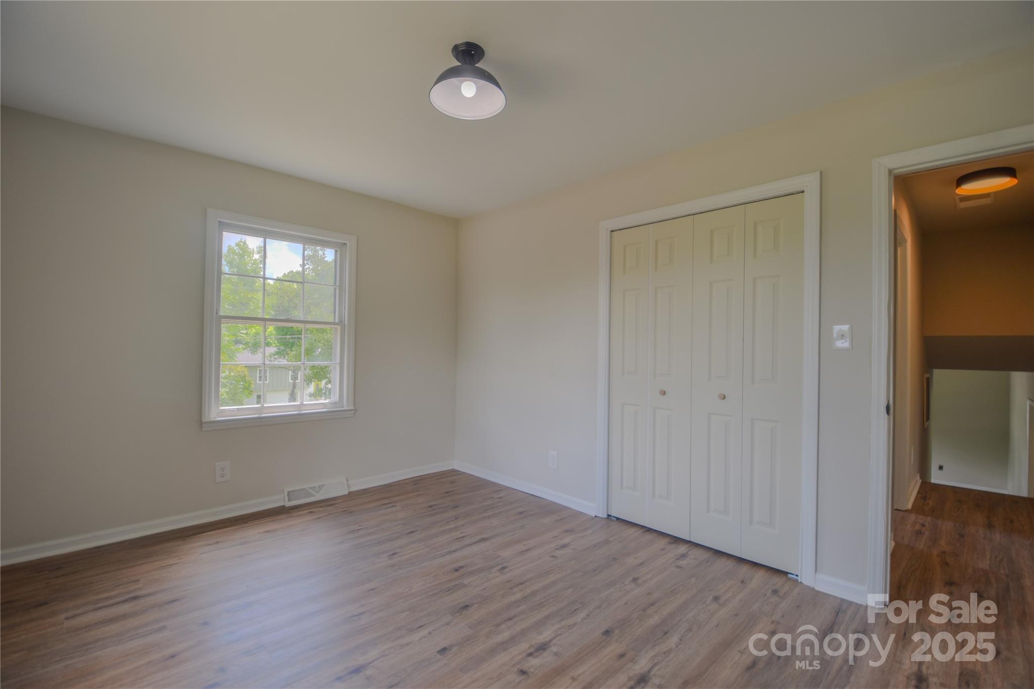 6921 Idlewild Road Charlotte, NC 28212 - Photo 15 of 29 a view of an empty room with wooden floor and a window