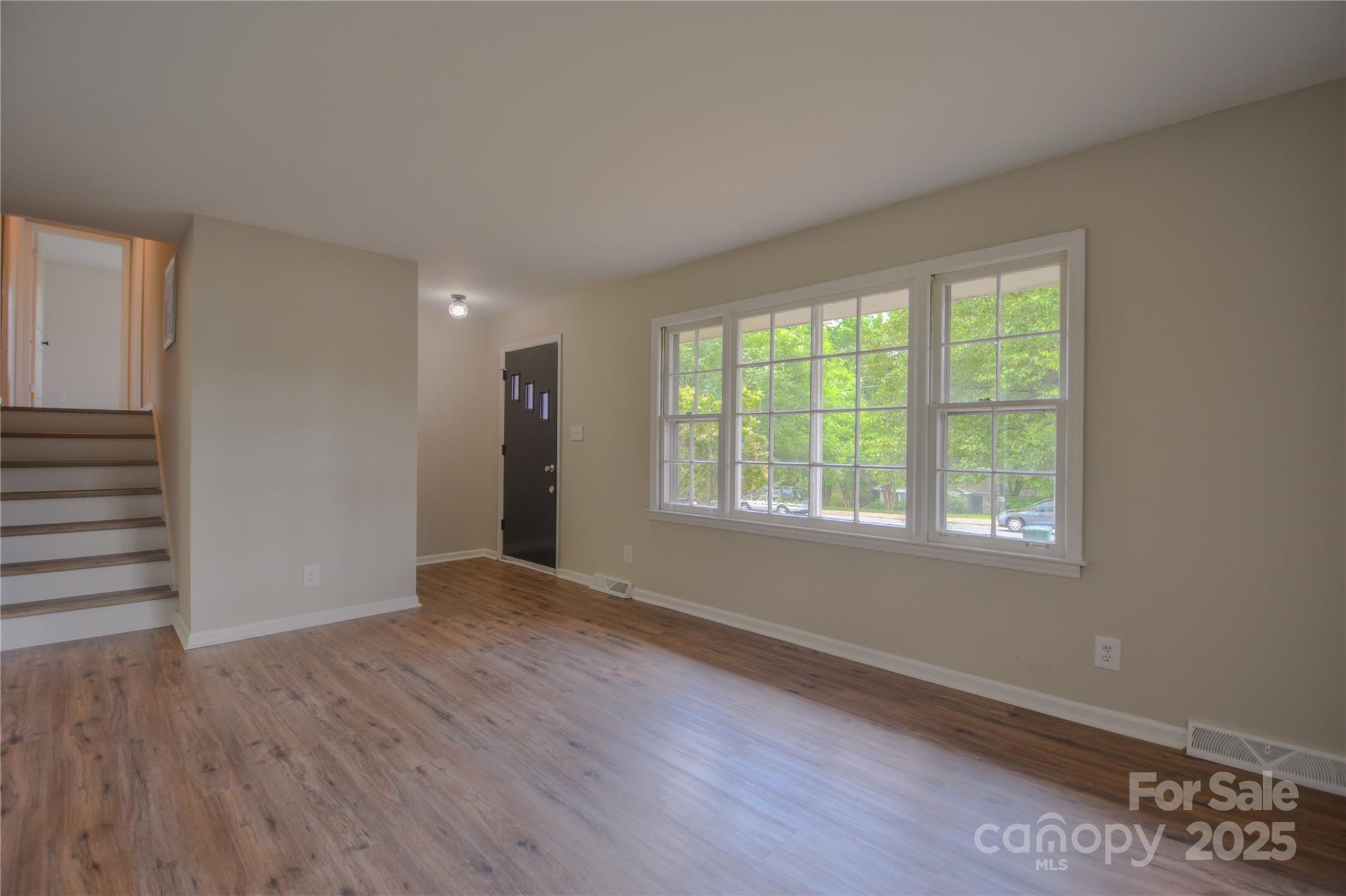 6921 Idlewild Road Charlotte, NC 28212 - Photo 3 of 29 a view of an empty room with wooden floor and a window