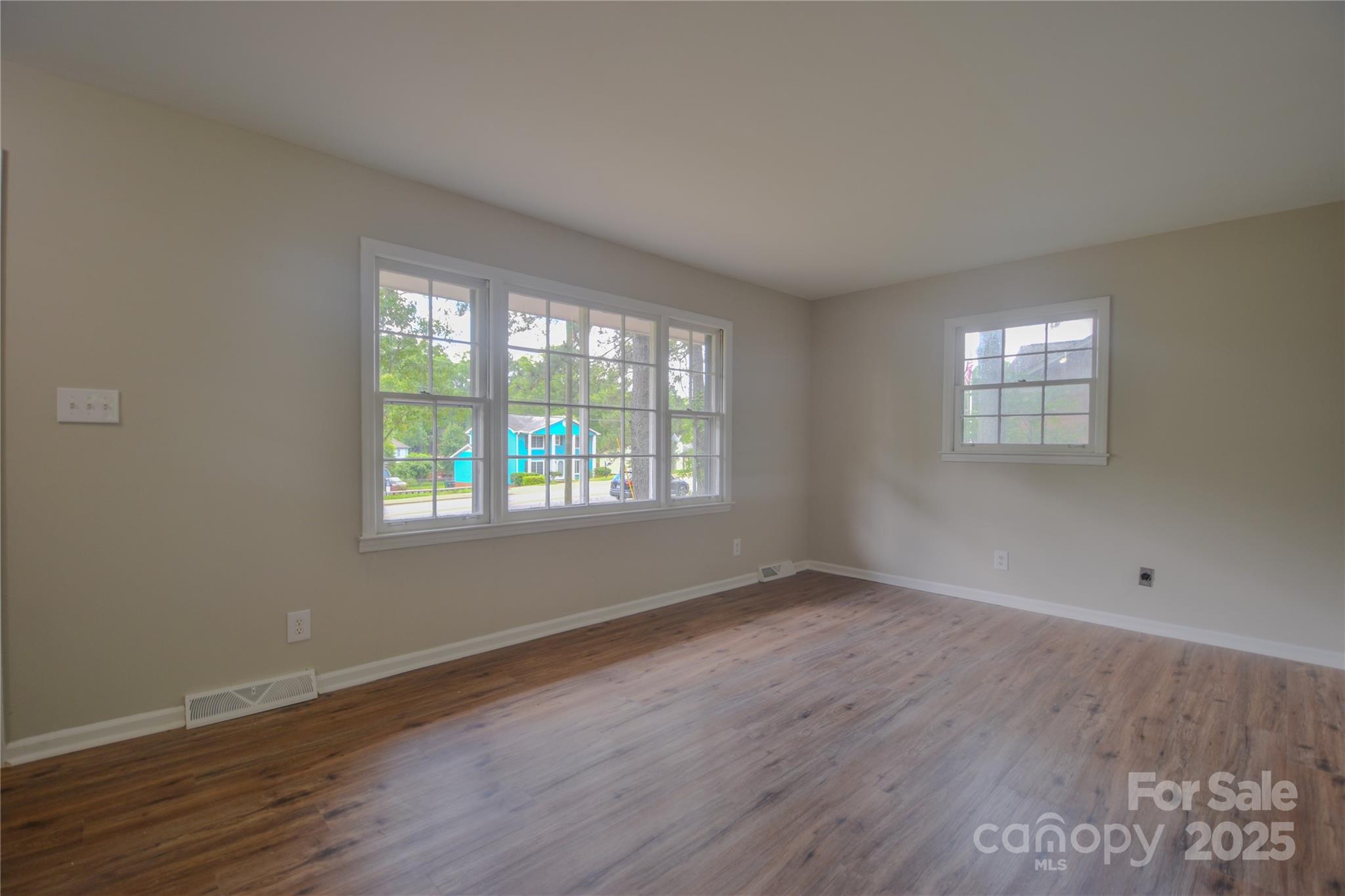 6921 Idlewild Road Charlotte, NC 28212 - Photo 5 of 29 an empty room with wooden floor and windows