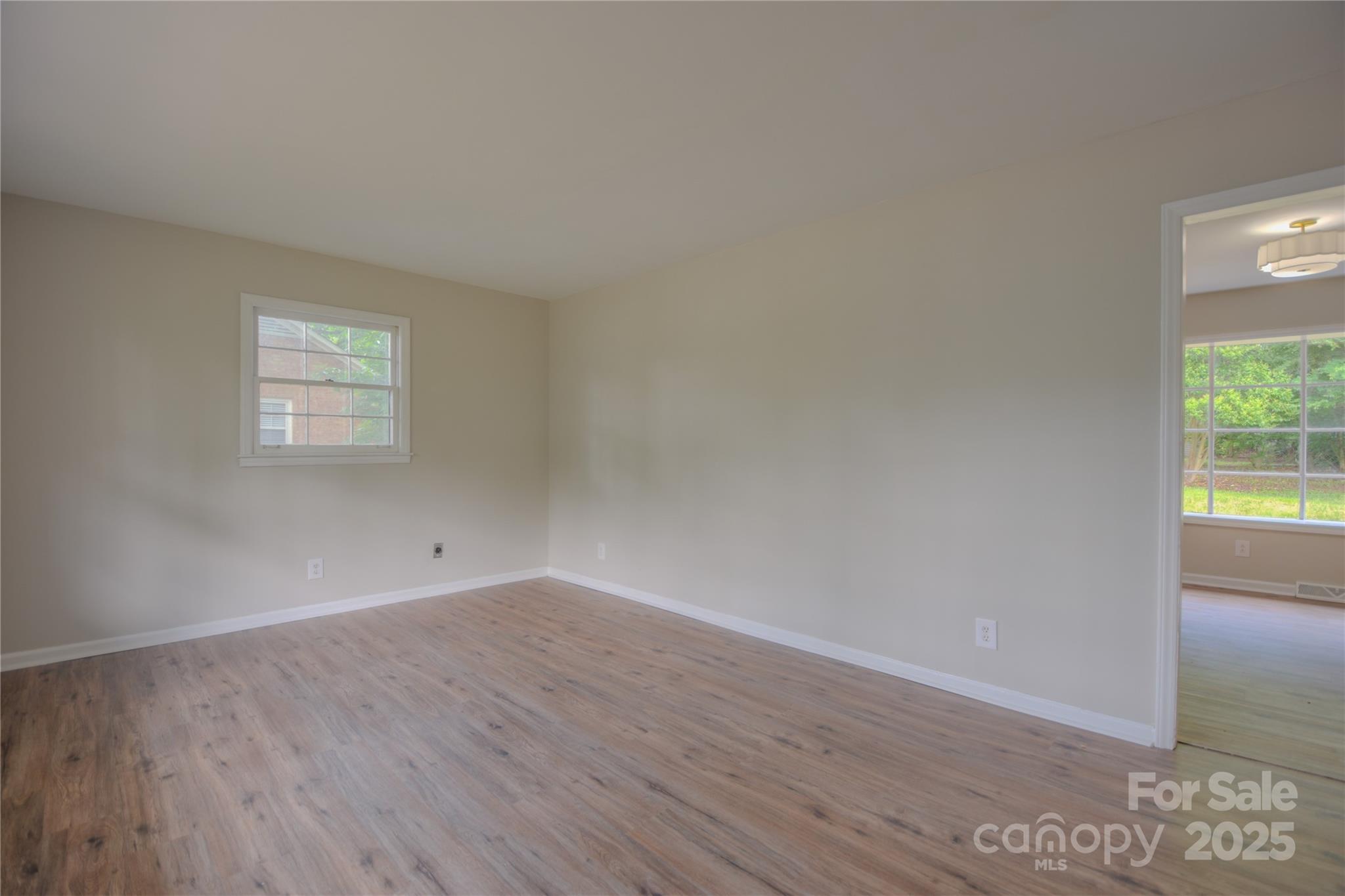 6921 Idlewild Road Charlotte, NC 28212 - Photo 6 of 29 an empty room with wooden floor and windows