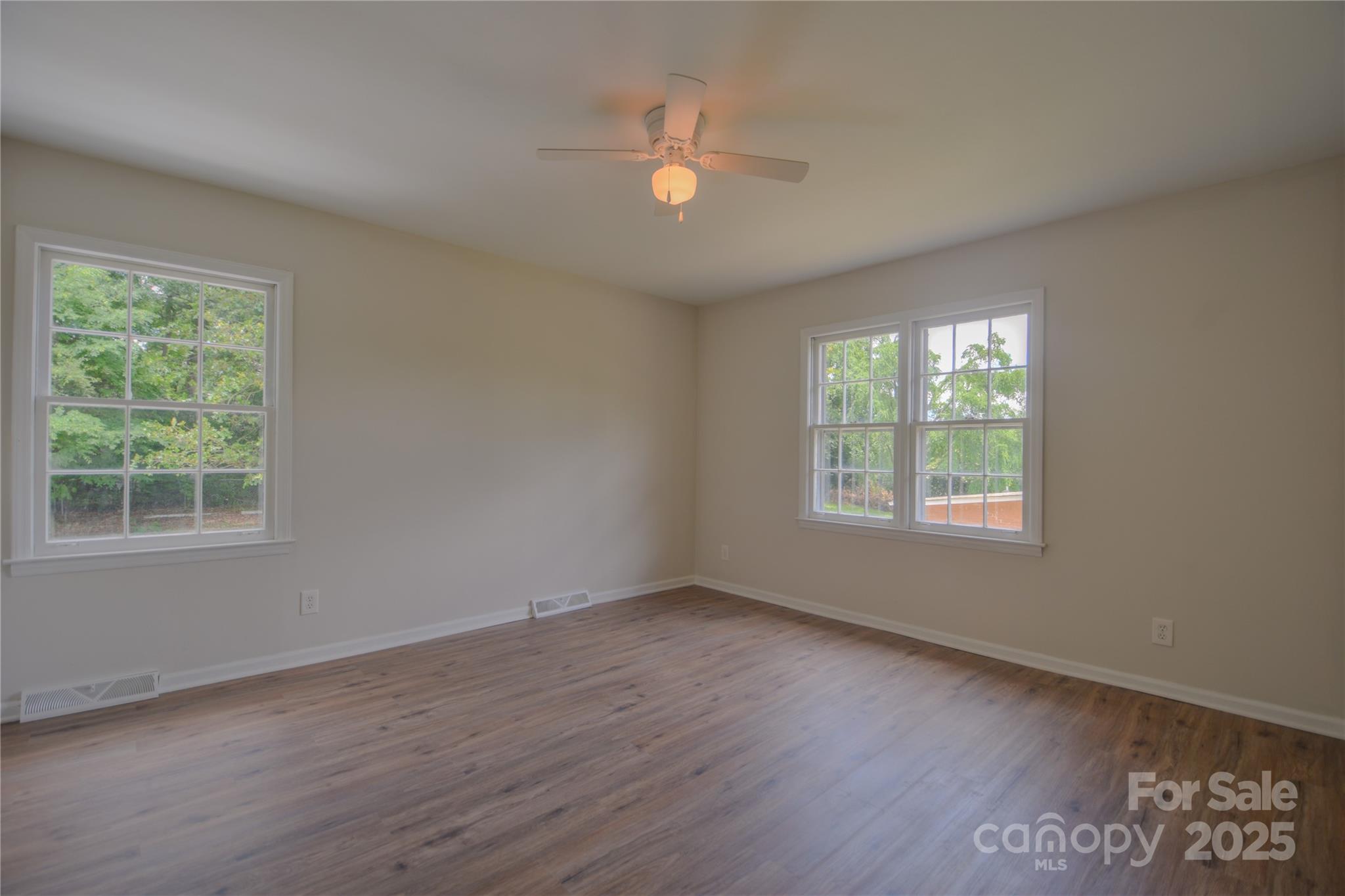 6921 Idlewild Road Charlotte, NC 28212 - Photo 10 of 29 an empty room with wooden floor and windows