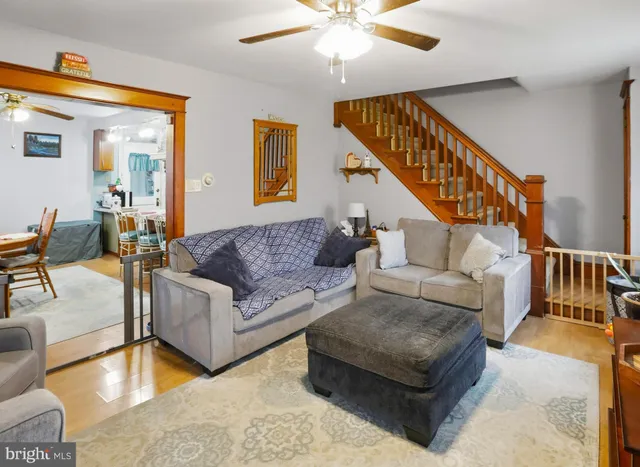 a living room with couches and a dining table with wooden floor