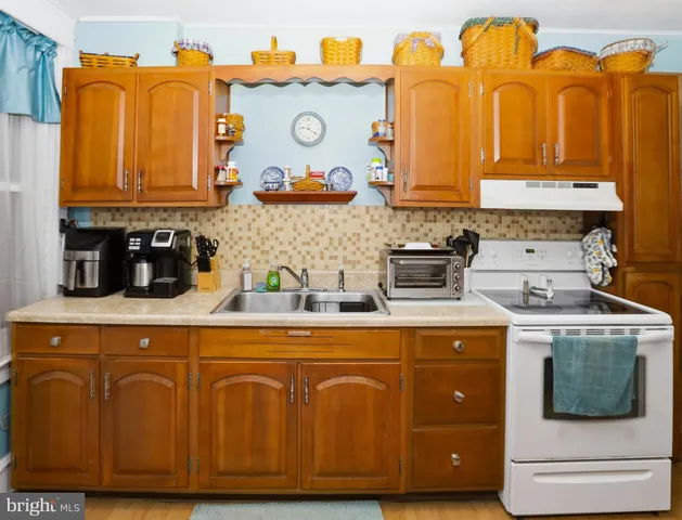 a kitchen with a refrigerator a stove a sink dishwasher and wooden cabinets with wooden floor