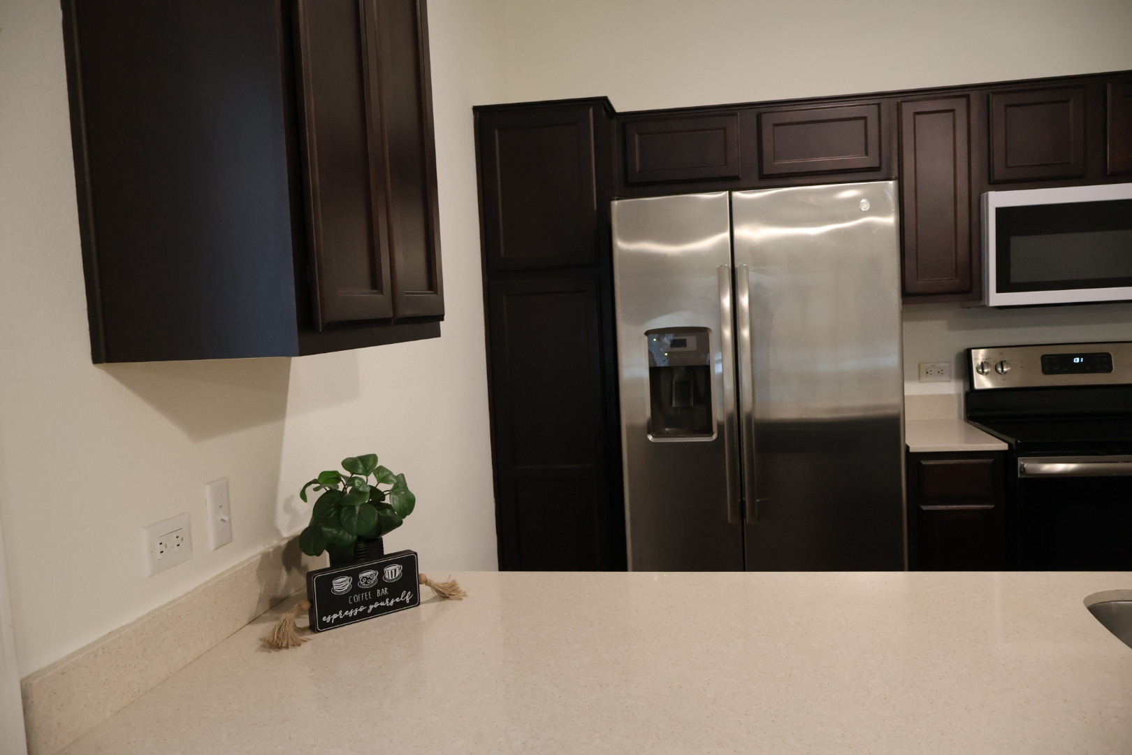 117 Galaxy Way Jarrell, TX 76537 - Photo 7 of 17 Kitchen featuring dark wood cabinetry, light-toned countertops, and stainless steel appliances