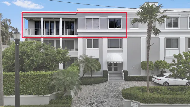 a view of a white house with large windows and a yard with plants