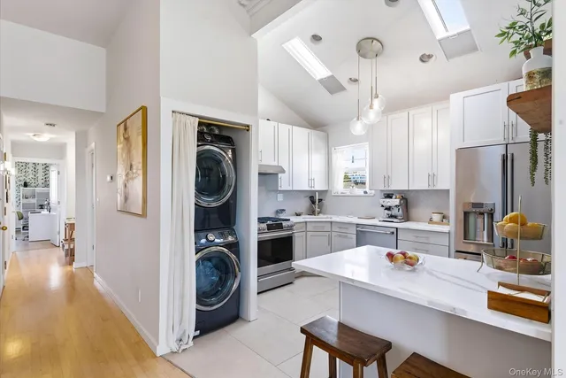 a open kitchen with stainless steel appliances granite countertop a refrigerator a stove a sink dishwasher and white cabinets with wooden floor