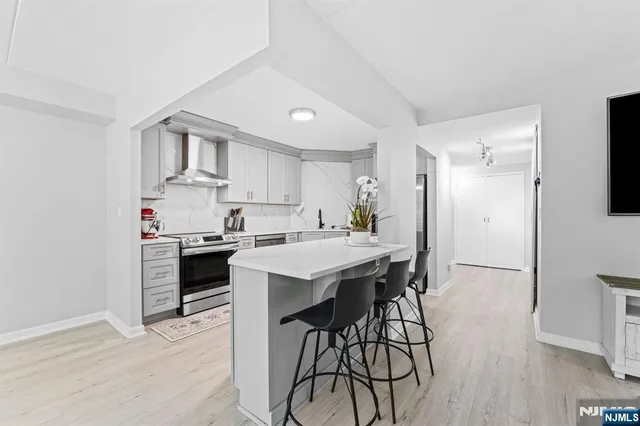 a kitchen with stainless steel appliances a stove a sink dishwasher a refrigerator with white cabinets and wooden floor