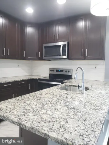 a kitchen with stainless steel appliances granite countertop a stove a sink and a microwave