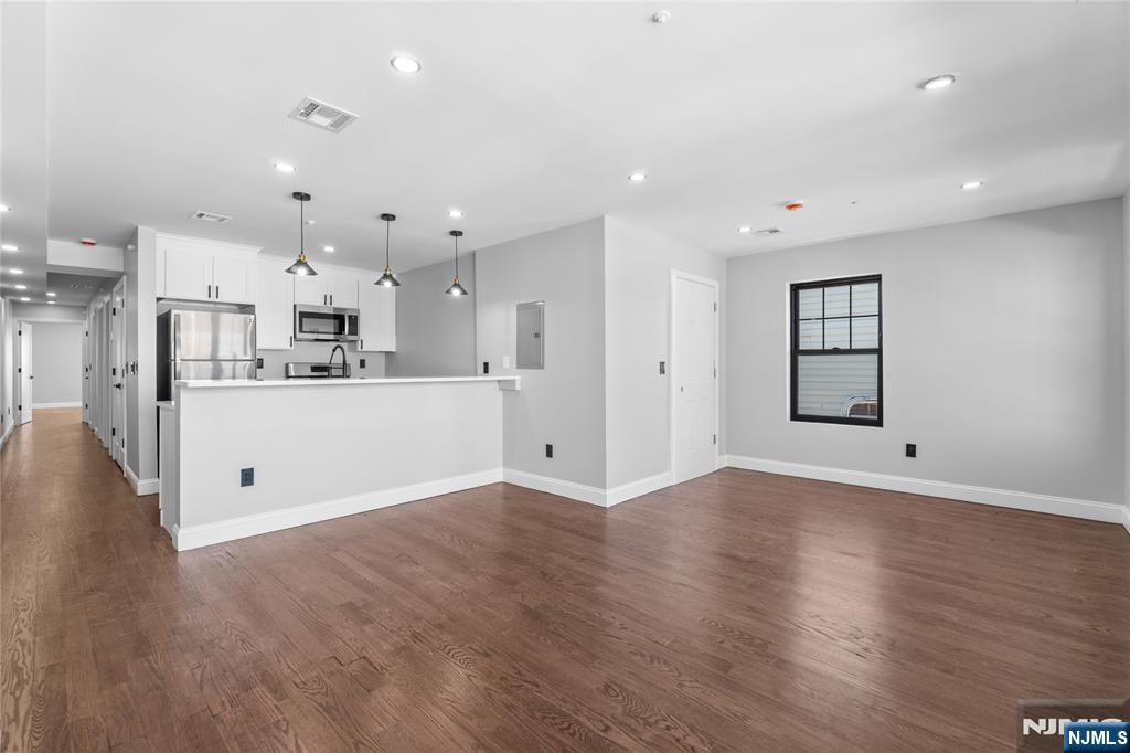 481 15th Avenue Newark, NJ 07103 - Photo 2 of 19 an empty room with wooden floor and a kitchen