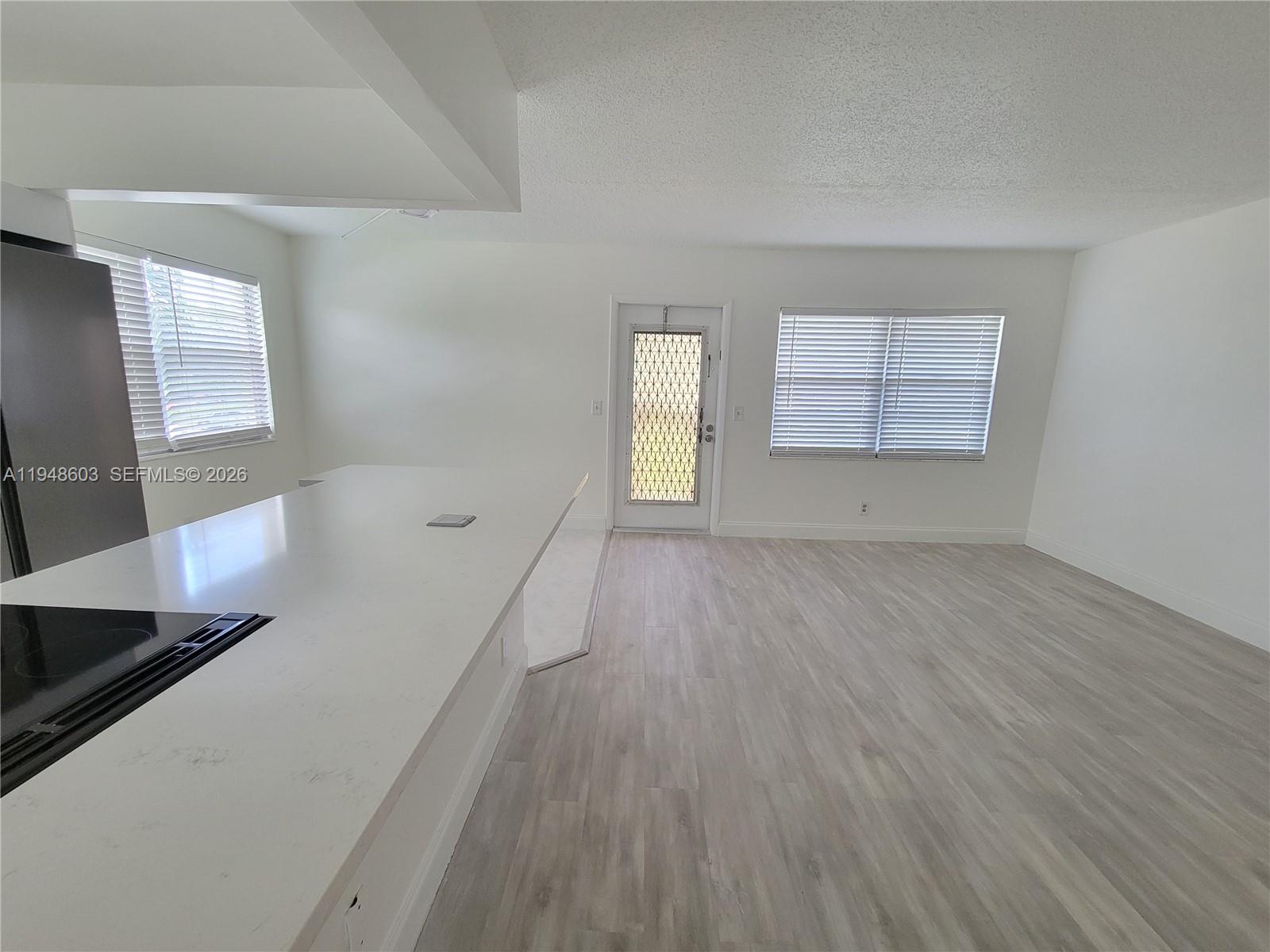 196 Mansfield F, Unit 196 Boca Raton, FL 33434 - Photo 14 of 58 an empty room with wooden floor and windows