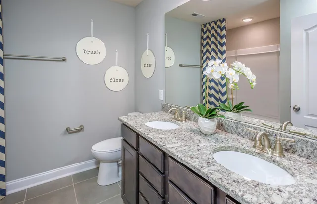 a bathroom with a granite countertop sink a toilet and a mirror