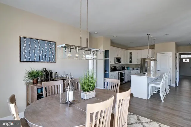 a kitchen with stainless steel appliances kitchen island granite countertop a refrigerator a stove a microwave a dining table and chairs with wooden floor