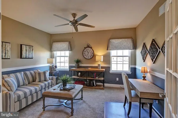 a living room with furniture a clock on wall and a window