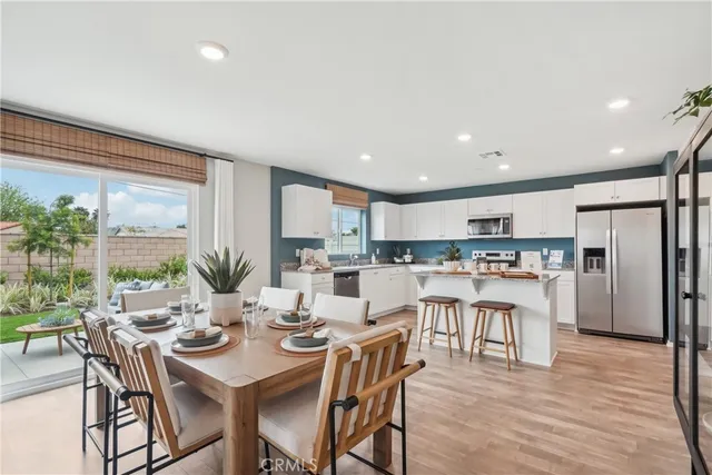 a kitchen with stainless steel appliances kitchen island granite countertop a dining table chairs and a refrigerator