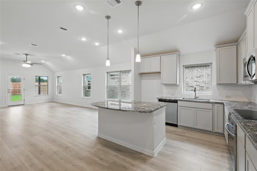 949 Schuberts Road Justin, TX 76247 - Photo 2 of 24 Kitchen with dark stone countertops, lofted ceiling, decorative backsplash, stainless steel appliances, and a kitchen island