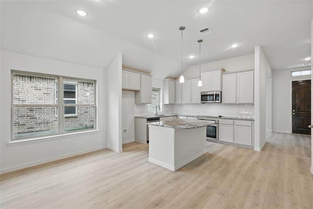 949 Schuberts Road Justin, TX 76247 - Photo 3 of 24 Kitchen featuring a center island, decorative light fixtures, light stone counters, stainless steel appliances, and white cabinetry