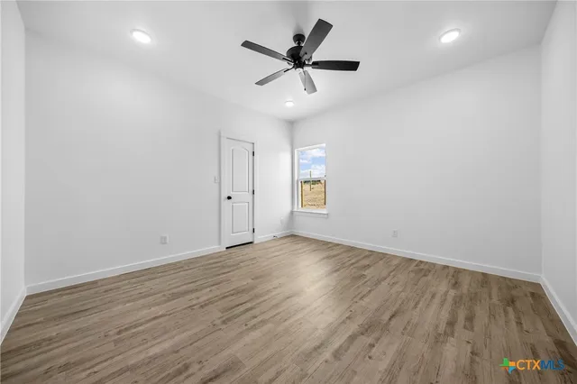 an empty room with wooden floor and ceiling fan