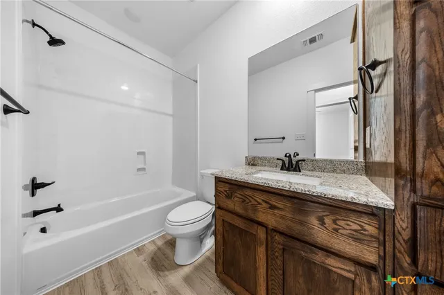 a bathroom with a granite countertop sink toilet vanity mirror bathtub and shower