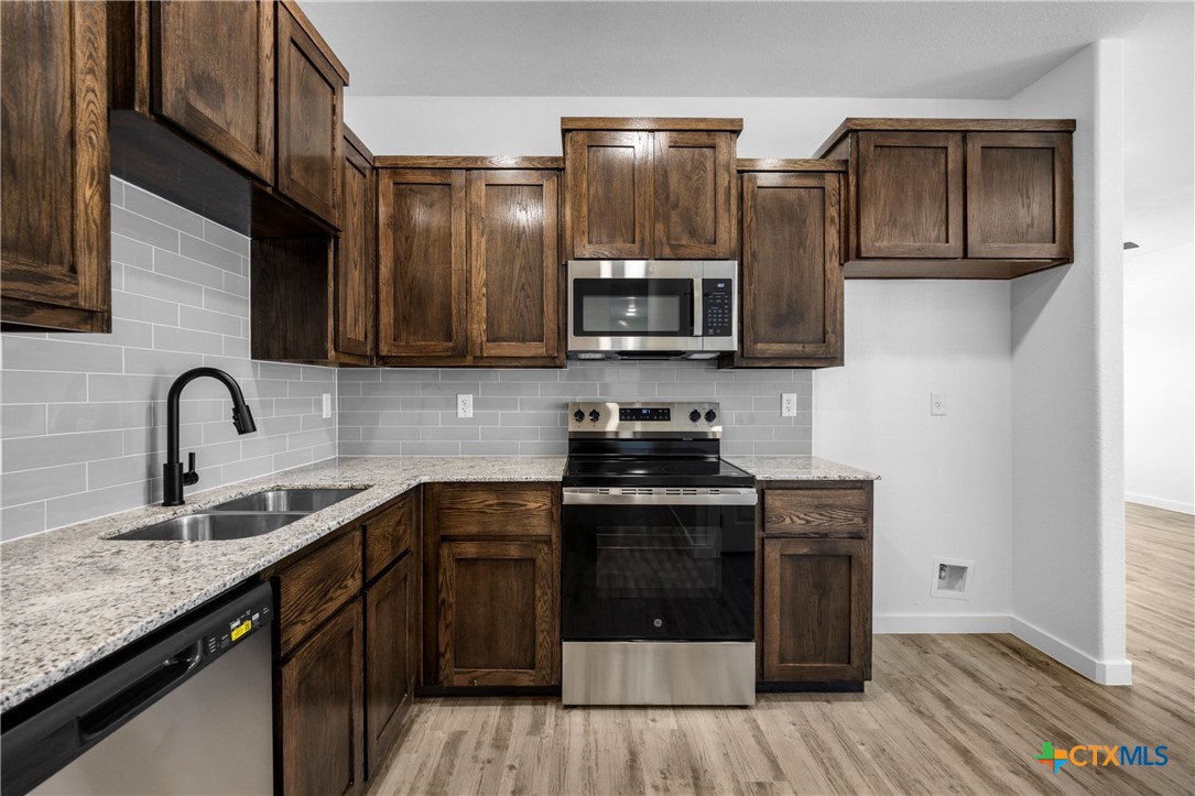 3606 Canvasback Road, Unit B Killeen, TX 76542 - Photo 17 of 19 a kitchen with stainless steel appliances granite countertop a stove a sink and a microwave