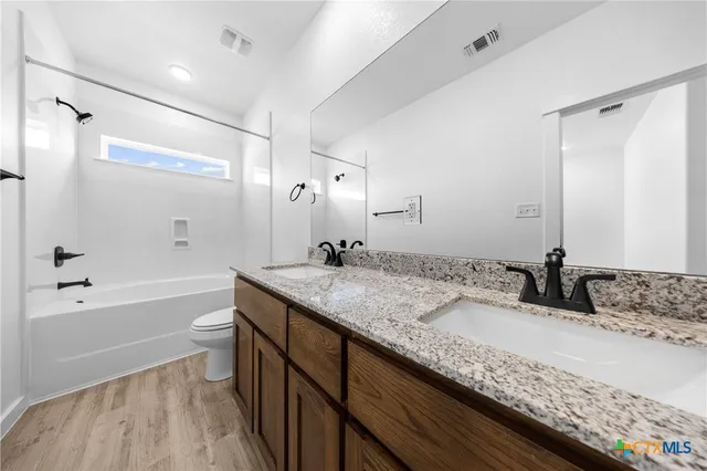 a bathroom with a granite countertop sink a toilet and shower