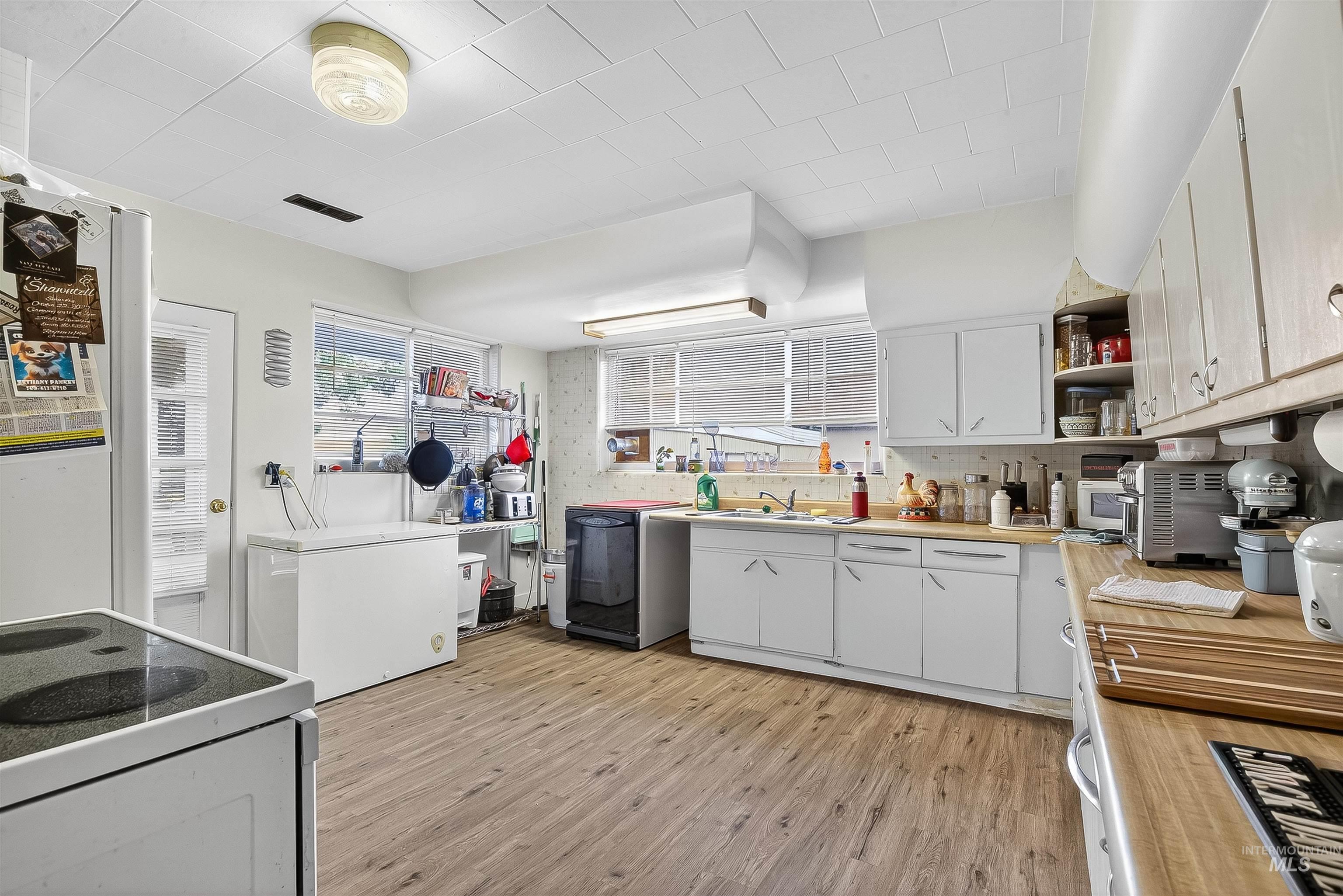 705 28th Street North Lewiston, ID 83501 - Photo 15 of 34 Kitchen with white cabinetry, light countertops, light wood finished floors, open shelves, and tasteful backsplash