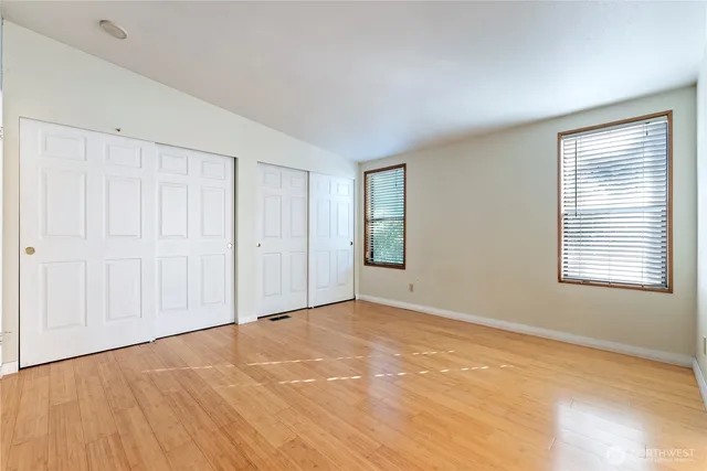 a view of an empty room with window and wooden floor