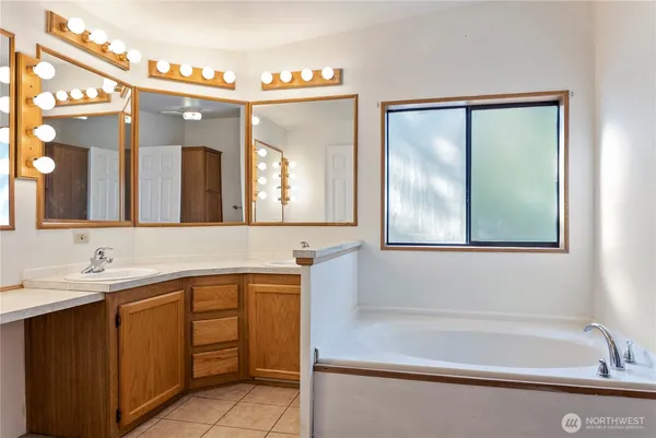 a bathroom with a tub a sink and mirror