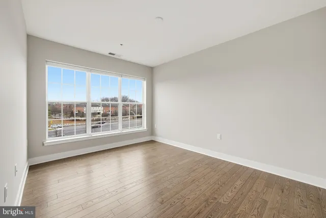 a view of an empty room with a window and wooden floor
