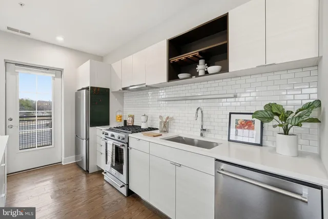 a kitchen with stainless steel appliances white cabinets and a stove top oven