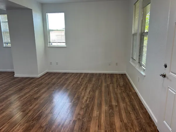 an empty room with wooden floor and windows