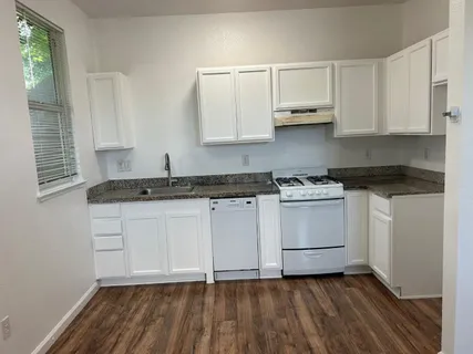 a kitchen with granite countertop white cabinets and white appliances