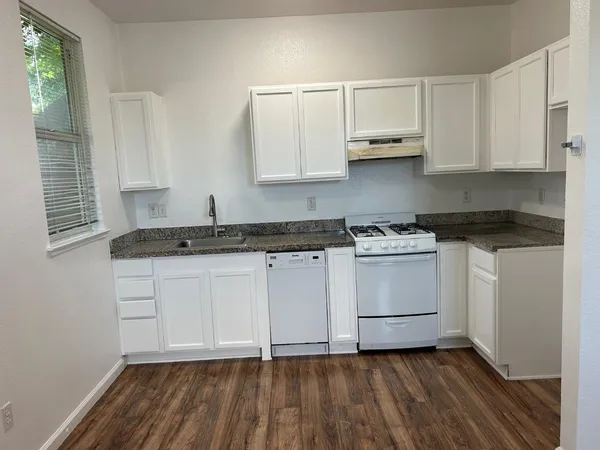 a kitchen with granite countertop white cabinets and white appliances