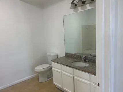 a bathroom with a granite countertop sink toilet and a mirror