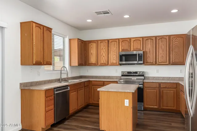 a kitchen with stainless steel appliances granite countertop a stove a sink and a refrigerator