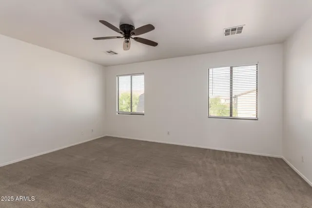 a view of a livingroom with a ceiling fan & windows