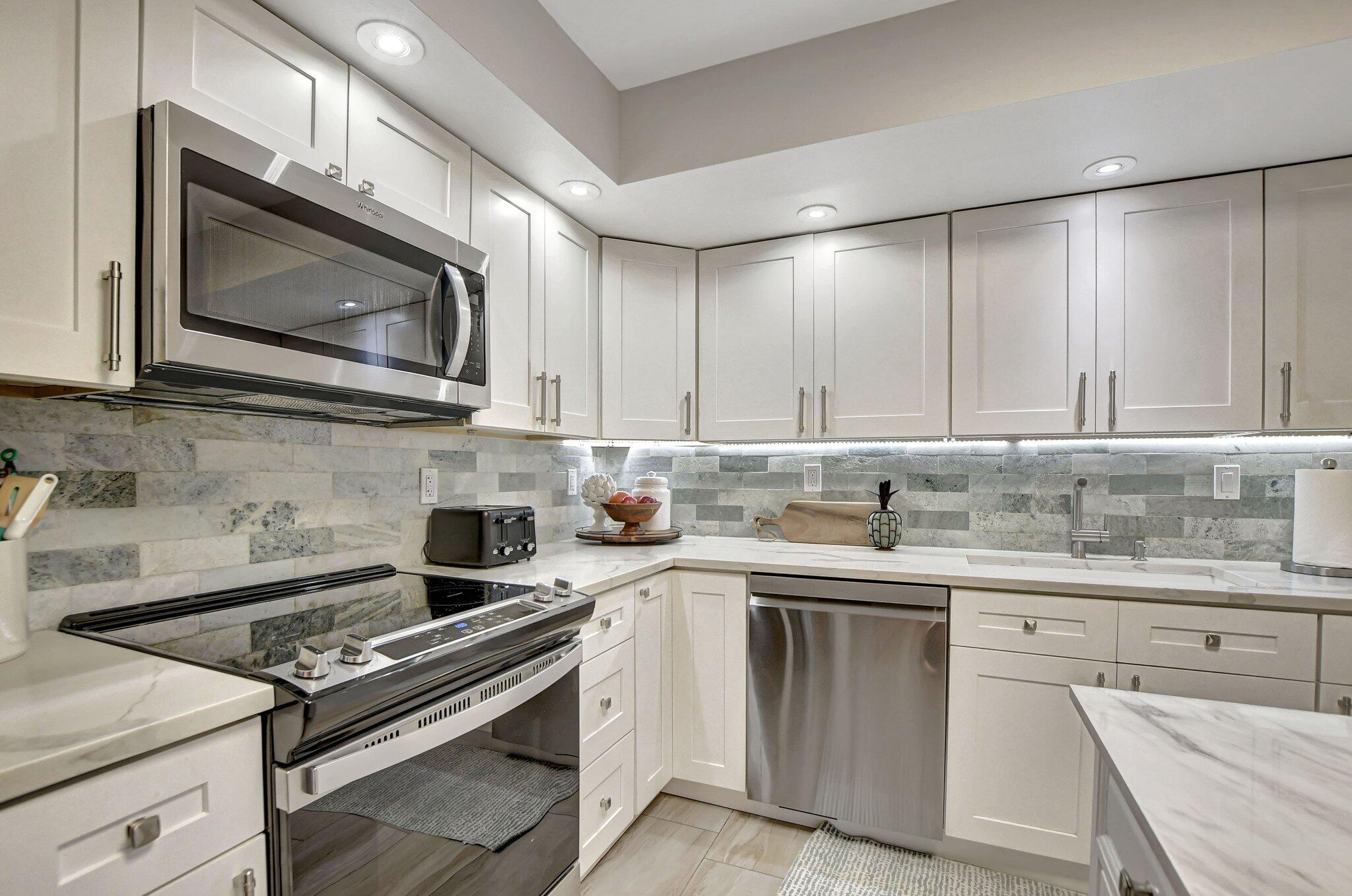 277 North Ocean Boulevard, Unit 3010 Boca Raton, FL 33432 - Photo 20 of 37 a kitchen with stainless steel appliances granite countertop a stove a microwave a sink and cabinets