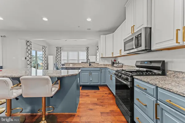 a kitchen with stainless steel appliances granite countertop a stove top oven a sink dishwasher and cabinets with wooden floor