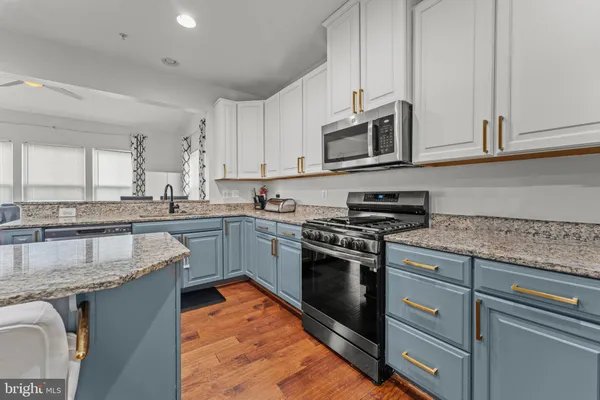 a kitchen with stainless steel appliances granite countertop a stove a sink and a microwave