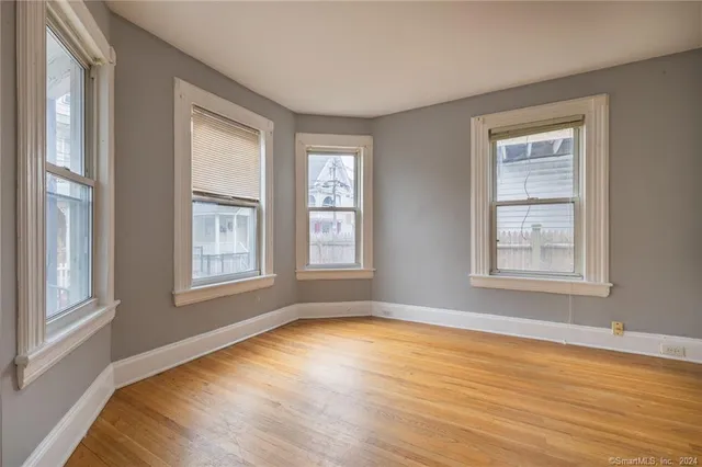 a view of an empty room with a window and wooden floor