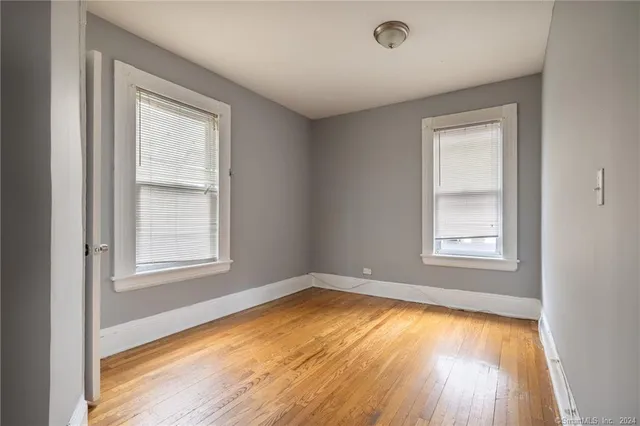 an empty room with a window and wooden floor