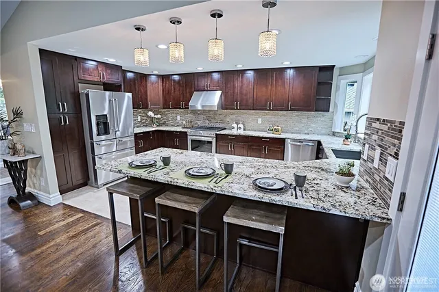 a kitchen with stainless steel appliances granite countertop a stove refrigerator and cabinets