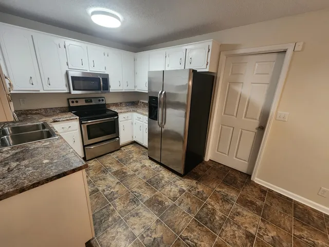a kitchen with granite countertop a refrigerator and a sink