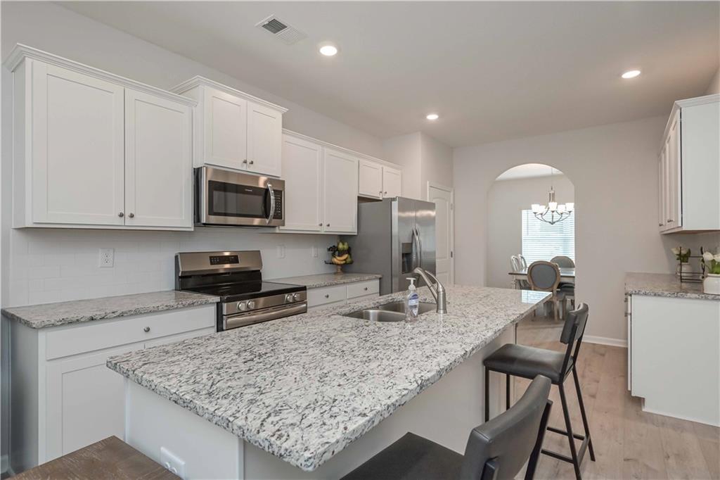 505 Charleston Place Villa Rica, GA 30180 - Photo 12 of 35 a kitchen with stainless steel appliances granite countertop a stove top oven a sink dishwasher and a microwave with wooden floor
